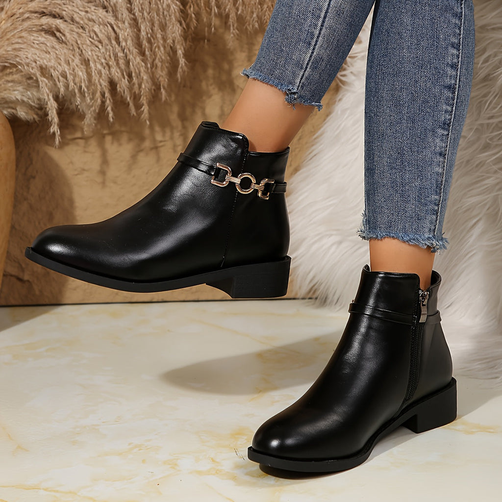Briar gold chain ankle boots in black leather, worn with jeans beside a fur throw