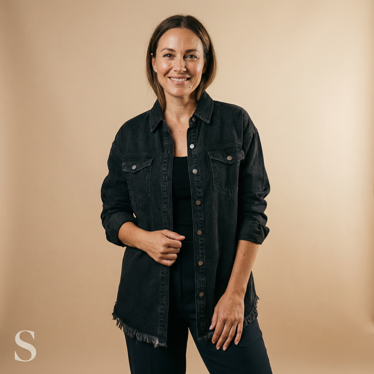 Woman wearing an oversized jean jacket with frayed hem and chest flap pockets over black jeans