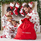Family wearing matching white Christmas pajamas with Santa sleigh and reindeer print and red trim