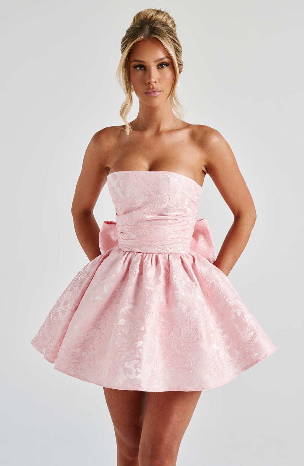 Strapless pink floral jacquard homecoming mini dress with oversized back bow and lace-up corset back