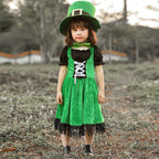 Girl wearing a green velvet leprechaun costume dress with lace-up front, black puff sleeves, fringed hem and tall buckled hat