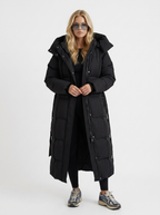 Model in a quilted hooded winter puffer jacket with self-tie belt