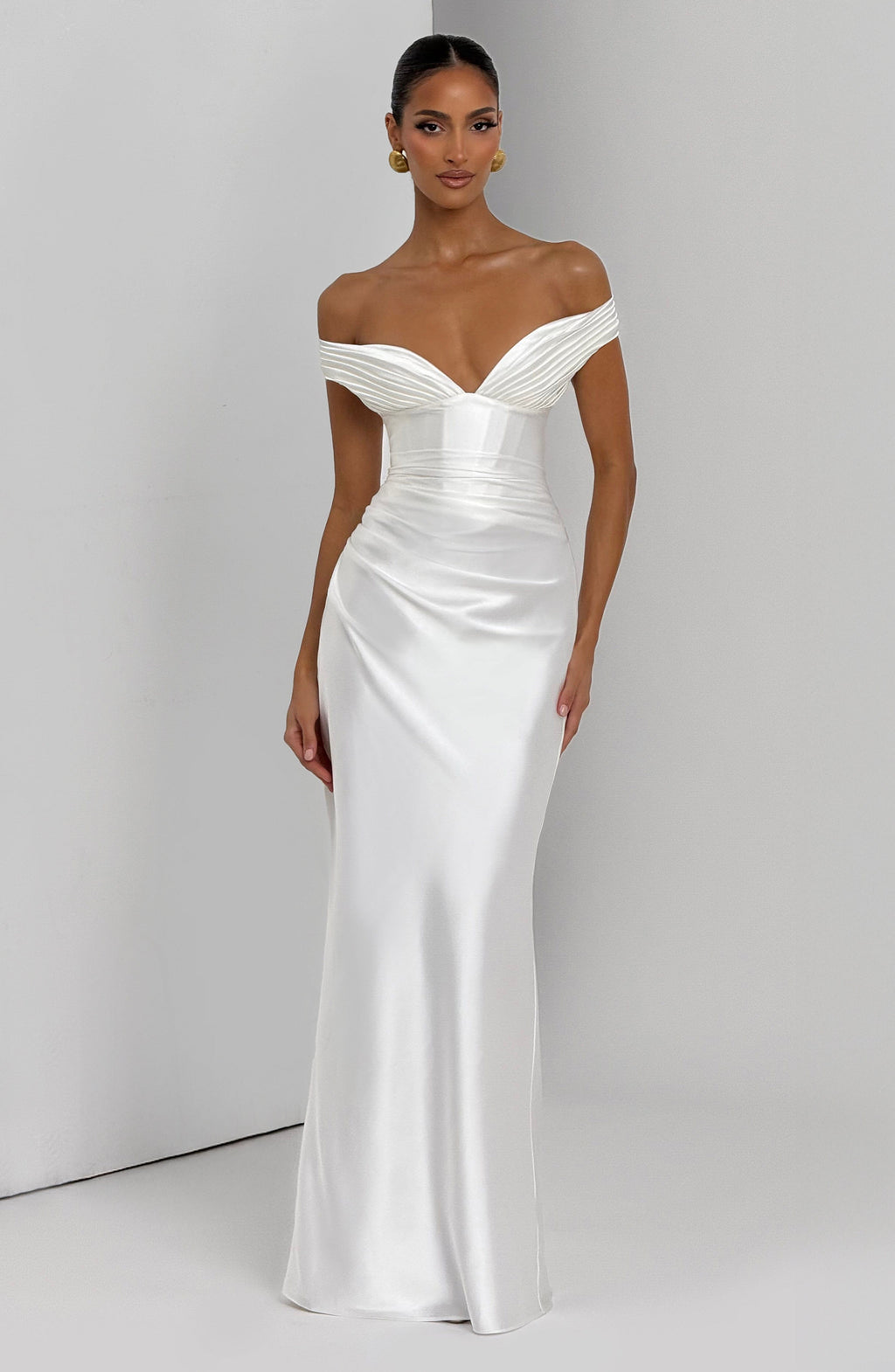 Woman wearing a satin off-shoulder maxi dress with pleated bust and corset bodice