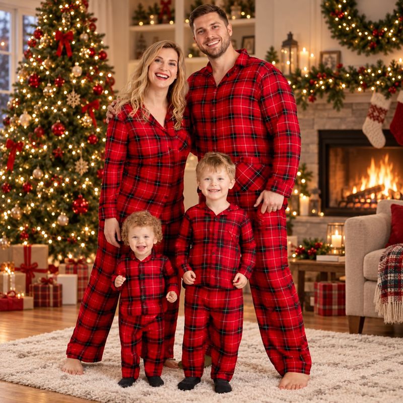 Family wearing matching red plaid Christmas pajamas by the tree