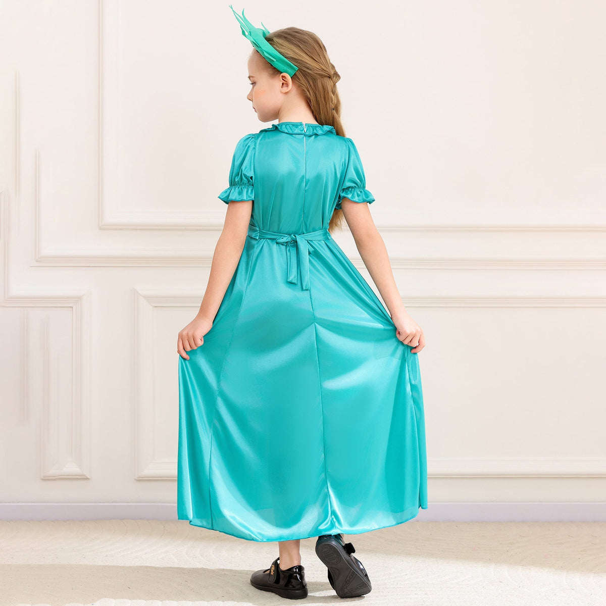 Girl wearing a teal satin-look Statue of Liberty costume dress with spiked crown headband and flame torch prop - view 2