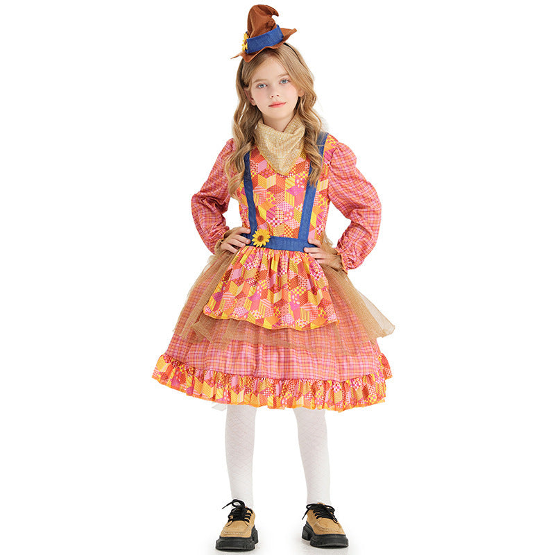 Girl wearing a pink plaid scarecrow Halloween costume dress with patchwork apron, sunflower and mini hat