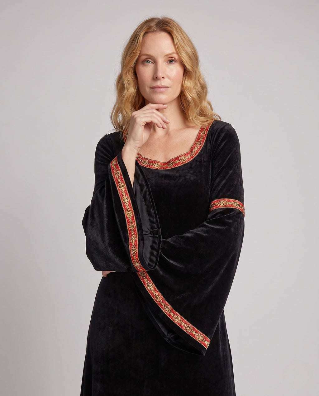Woman wearing a black velvet hooded costume dress with bell sleeves and red and gold trim - view 2