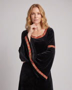 Woman wearing a black velvet hooded costume dress with bell sleeves and red and gold trim - view 2