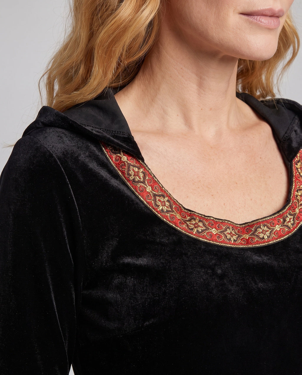 Woman wearing a black velvet hooded costume dress with bell sleeves and red and gold trim - view 3