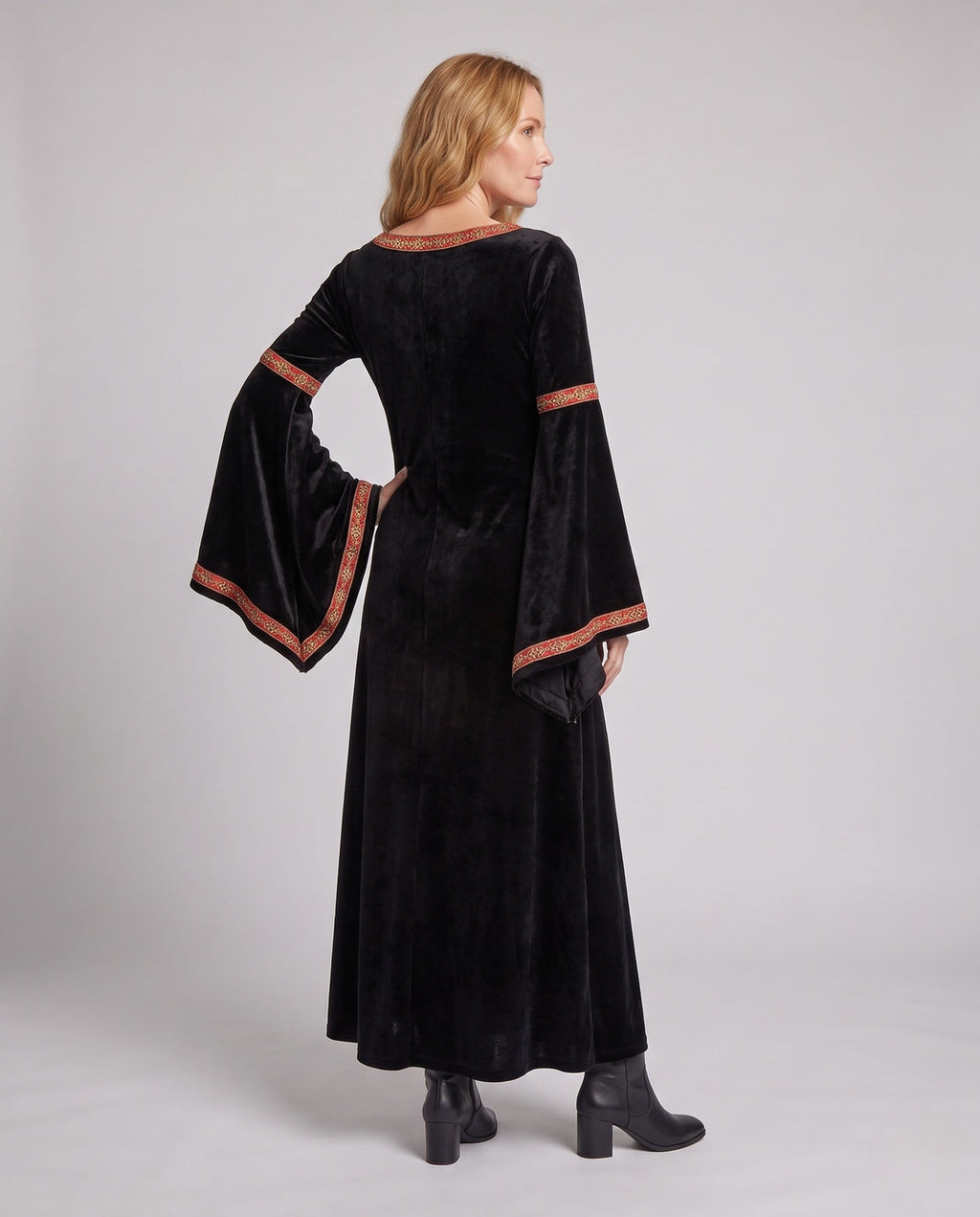Woman wearing a black velvet hooded costume dress with bell sleeves and red and gold trim - view 4