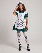 Woman wearing green Halloween costume dress with white bat-print ruffled apron