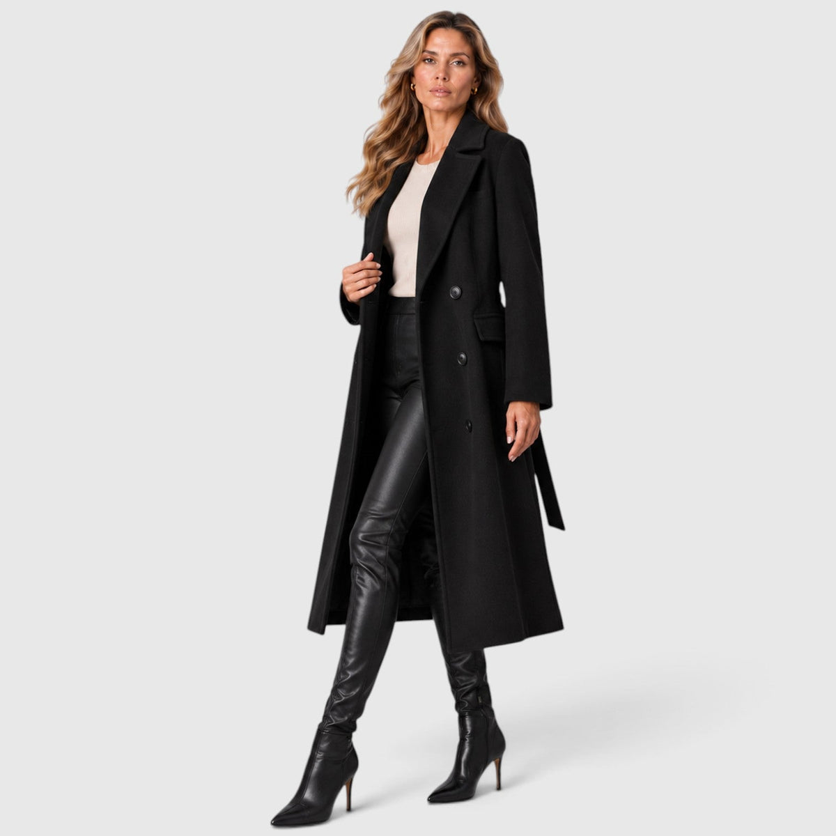Woman wearing a long double breasted belted coat with wide lapels and knee-high boots - view 2