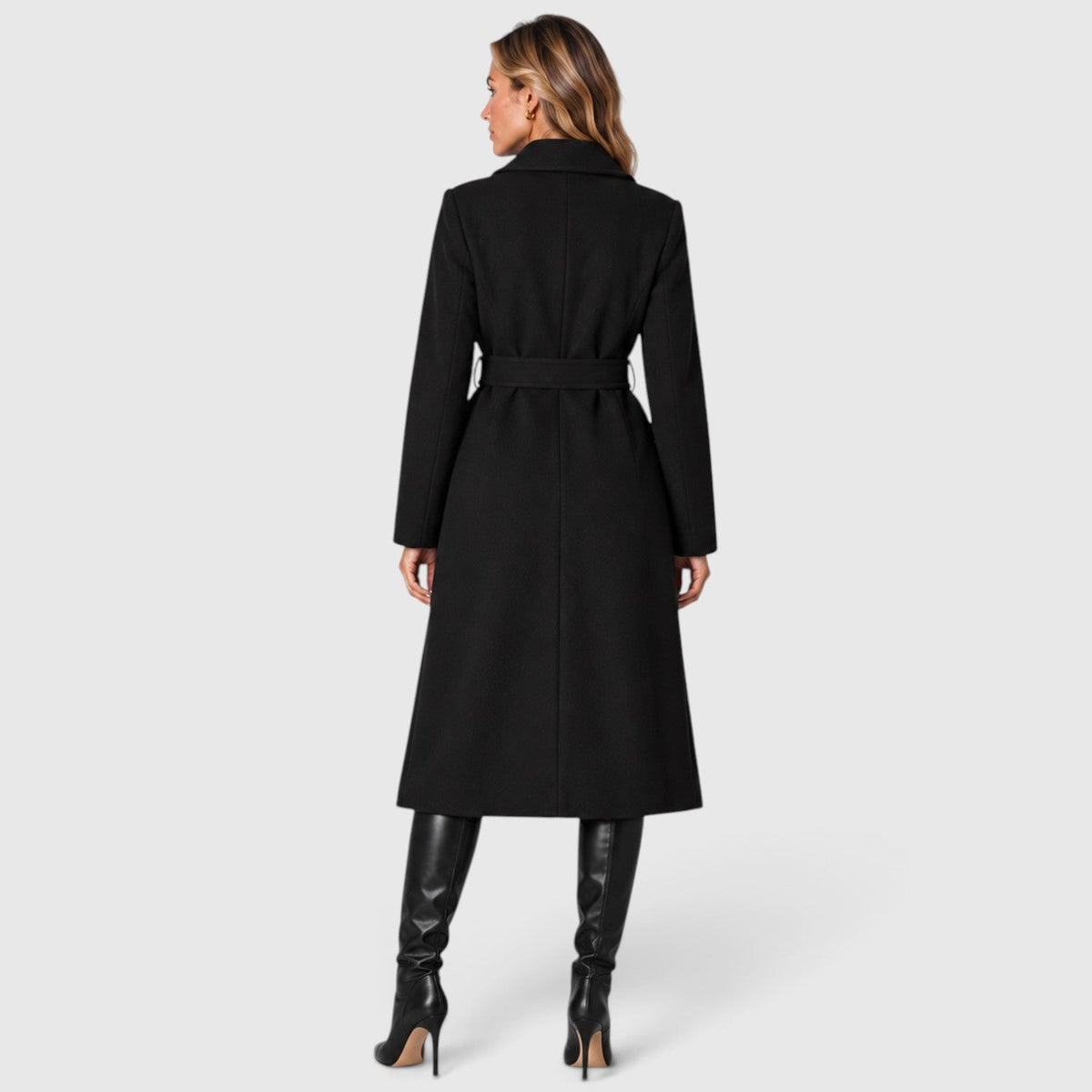 Woman wearing a long double breasted belted coat with wide lapels and knee-high boots - view 3