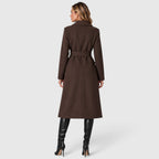 Woman wearing a long double breasted belted coat with wide lapels and knee-high boots - view 6