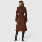 Woman wearing a long double breasted belted coat with wide lapels and knee-high boots - view 9