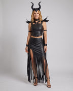 Woman in black leather-look horned Halloween costume with O-ring halter crop top and fringed slit skirt