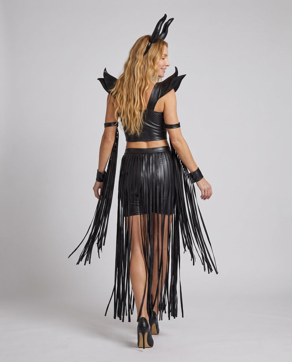 Woman in black leather-look horned Halloween costume with O-ring halter crop top and fringed slit skirt - view 4