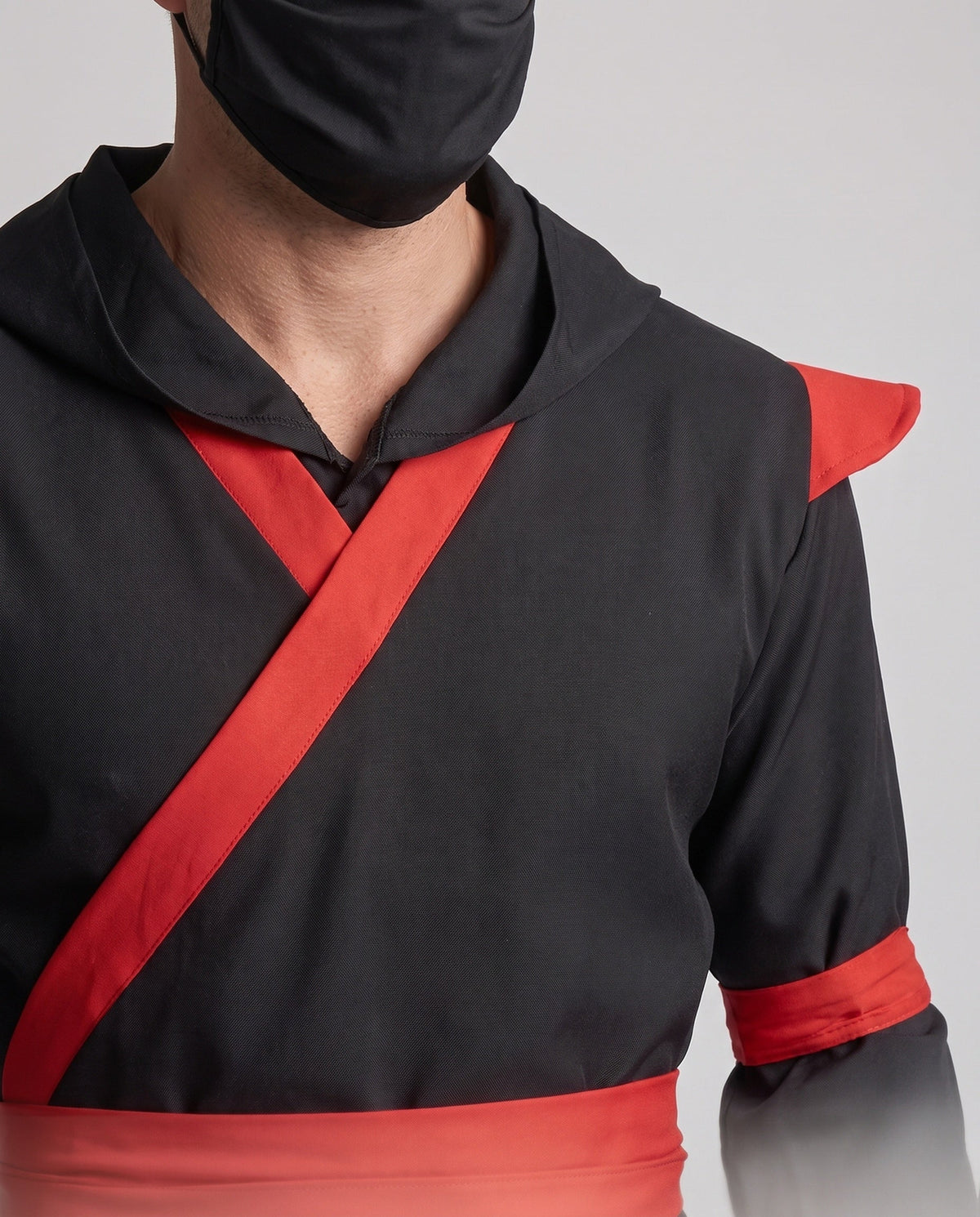 Men's black ninja Halloween costume with hood, red wrap trim, red sash and red leg wraps - view 2
