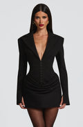 Long sleeve blazer-style homecoming mini dress with peak lapels, hook-front corset bodice and draped hip