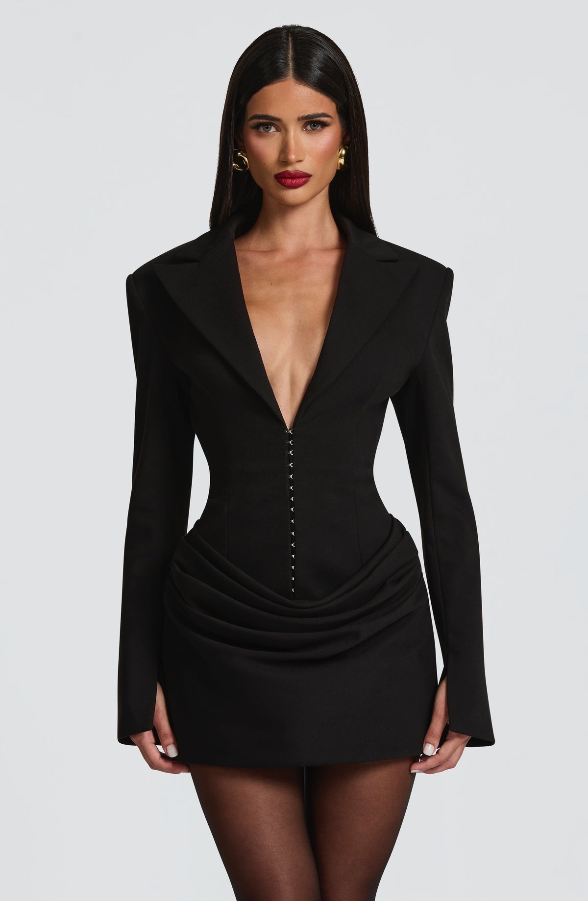 Long sleeve blazer-style homecoming mini dress with peak lapels, hook-front corset bodice and draped hip
