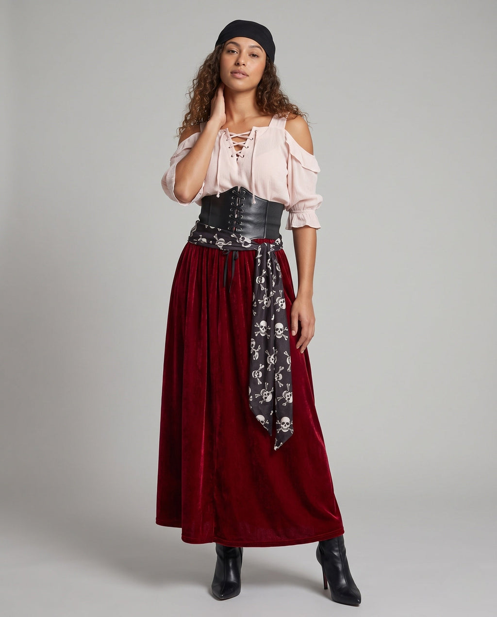 Women's pirate costume with blush lace-up cold-shoulder blouse, black corset belt, skull print sash and wine velvet maxi skirt