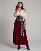 Women's pirate costume with blush lace-up cold-shoulder blouse, black corset belt, skull print sash and wine velvet maxi skirt