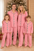 Family wearing matching red and white candy cane striped button-up Christmas pajamas with green piping