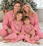Family wearing matching red and white candy cane striped button-up Christmas pajamas with green piping - view 2