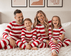Family in matching red and white striped Christmas pajamas with gray ribbed cuffs