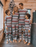 Family wearing matching Fair Isle Christmas pajamas with reindeer and snowflake print and white cuffs