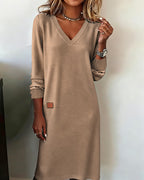 Woman wearing a relaxed V-neck midi sweater dress with raglan long sleeves and striped cuffs