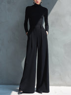 Woman in black long sleeve wide leg jumpsuit with turtleneck and pleated legs