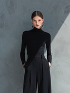 Woman in black long sleeve wide leg jumpsuit with turtleneck and pleated legs - view 2