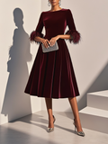 Burgundy velvet feather cocktail dress with A-line midi skirt and feather-trimmed cuffs