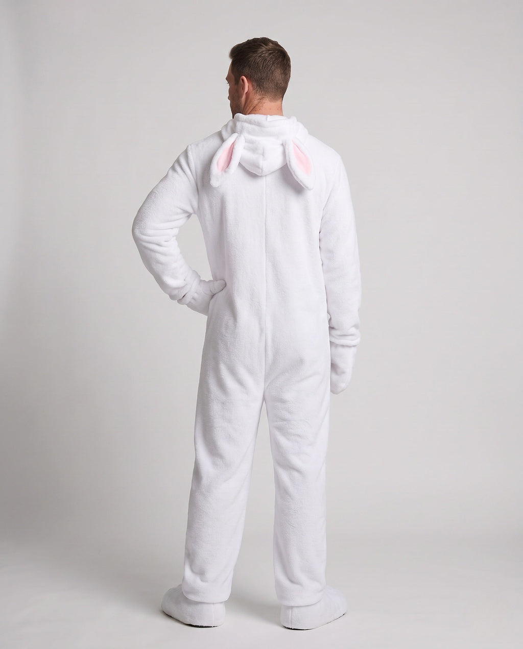 Man wearing a white plush bunny costume jumpsuit with pink belly panel and eared hood - view 3