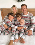 Family wearing matching gray Fair Isle Christmas pajamas with red reindeer and green tree stripes - view 2