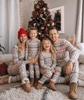 Family wearing matching fair isle Christmas pajamas with reindeer and tree print