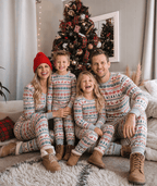 Family wearing matching fair isle Christmas pajamas with reindeer and tree print