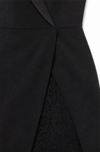 Woman wearing a fitted tuxedo-collar cocktail dress with sheer lace sleeves and lace skirt panel - view 9